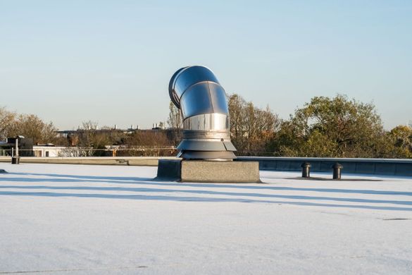 Metal ventilation system on a white flat roof against a clear sky.