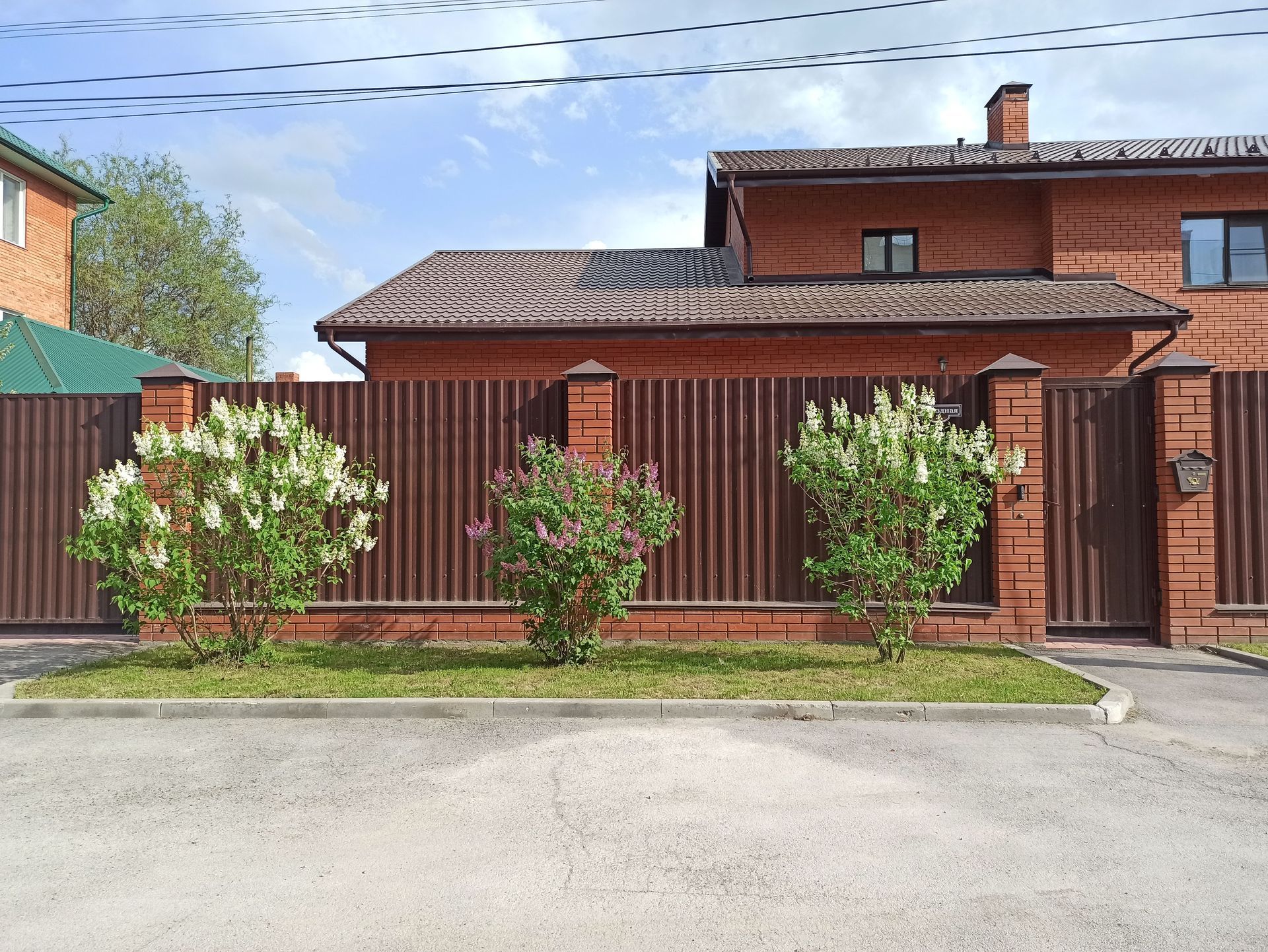 Brown slatted fence between brick pillars outside a house