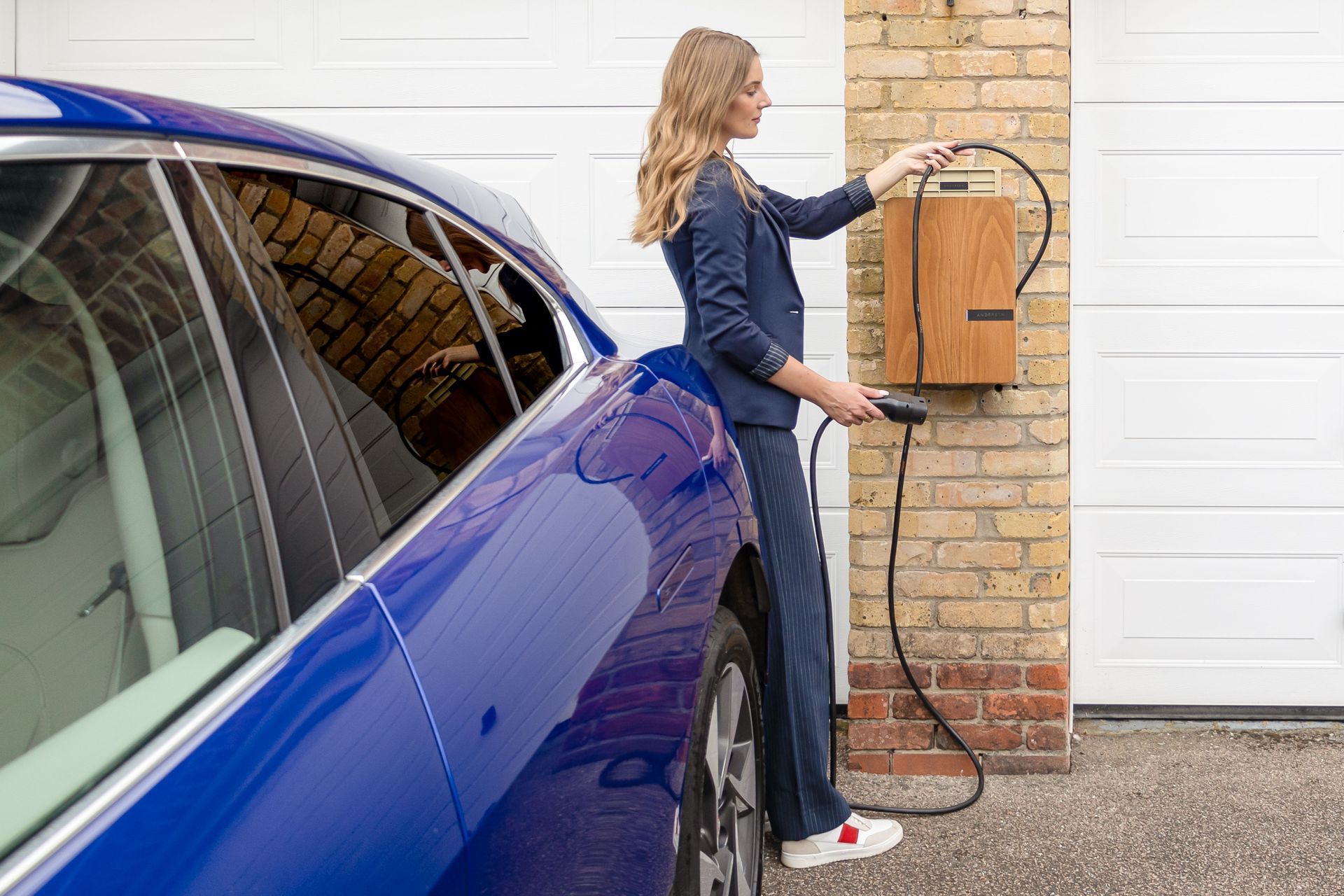 Woman plugging an electric car into a home charger
