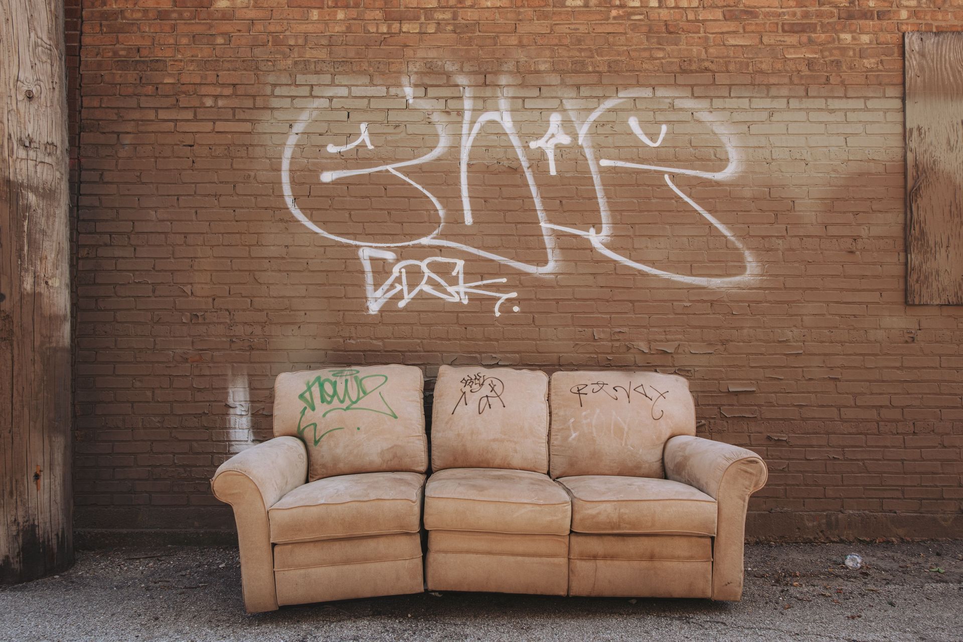 Old sofa left outside against a brick wall waiting for bulky waste collection