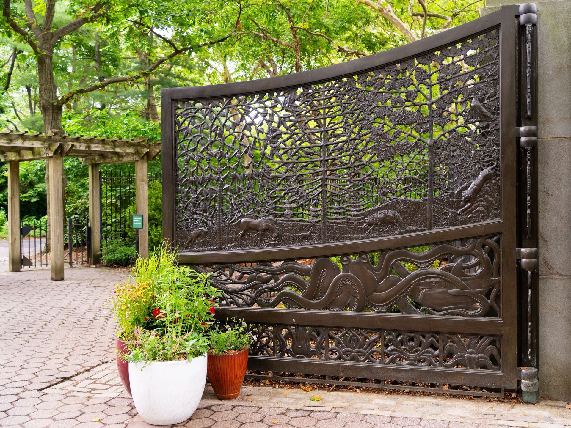 Decorative metal garden gate beside planting