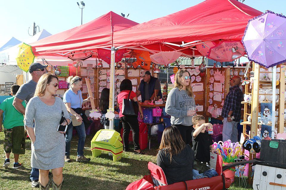 A group of people are standing under tents at a festival.