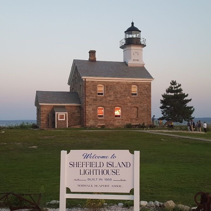 Sheffield Island Lighthouse at dusk with sign in front.