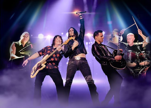 A band performing on stage under purple lights. Musicians play guitars, drums, and sing, with a lead singer center.