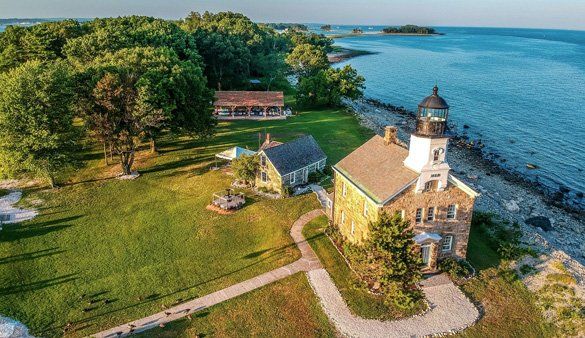 An aerial view of a lighthouse on a small island next to the ocean.