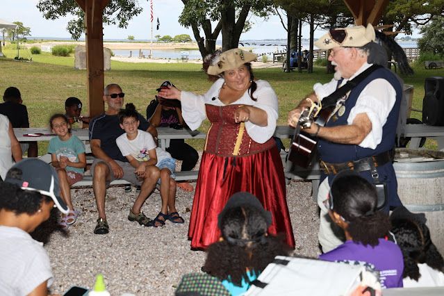 A man is playing a bagpipe and a woman is dancing in front of a group of people