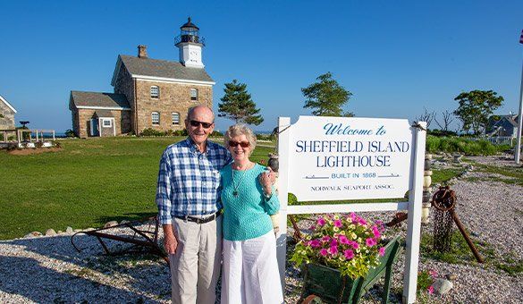 A man and woman are posing for a picture in front of a lighthouse.