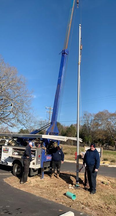 A group of men are working on a pole with a crane.