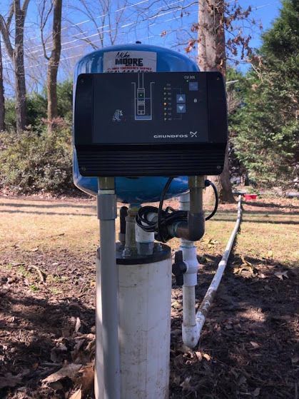A water pump is sitting on top of a white pipe.