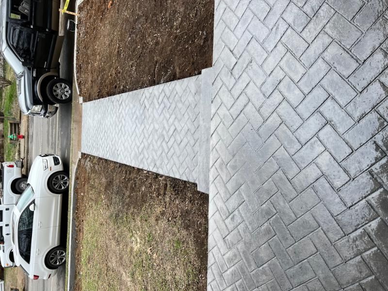 Diagonal brick walkway between parked cars and brown grass in a residential area