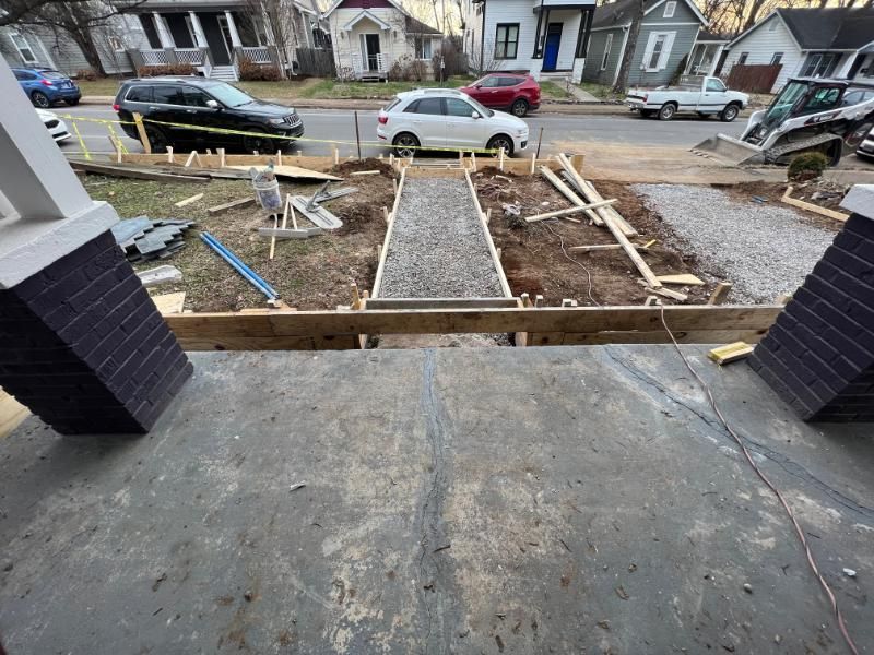 Front porch view of a dirt-lined walkway under construction leading to the sidewalk, with parked cars in front.