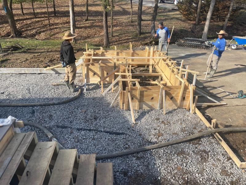 Workers building a wooden foundation frame on gravel at an outdoor construction site