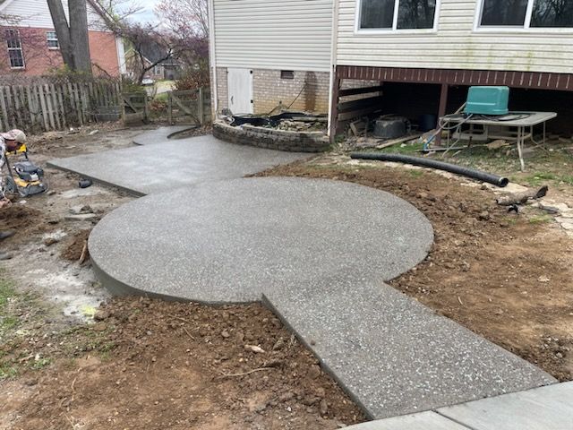 Freshly poured concrete patio and walkway beside a house under construction.