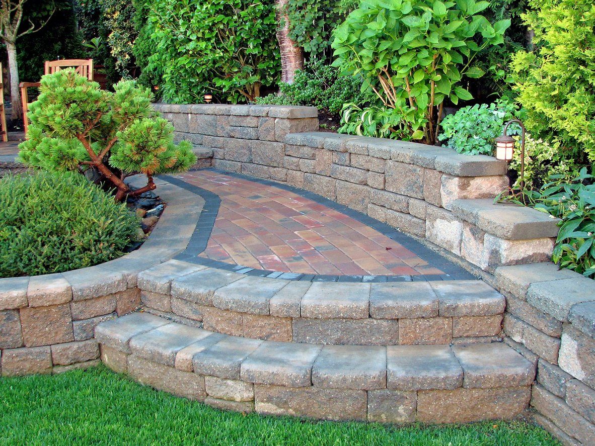 Curved stone steps leading to a tiled patio in a lush garden