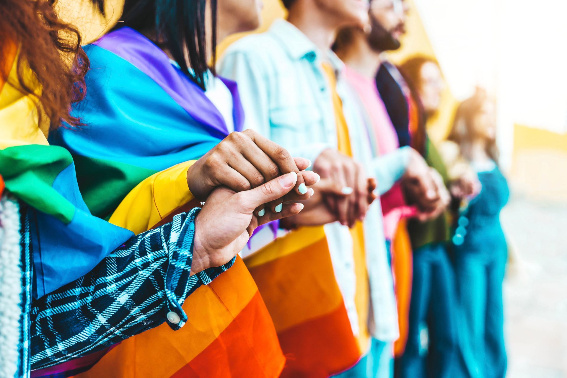 A group of people holding hands with a rainbow flag. A group of people holding hands with a rainbow flag.