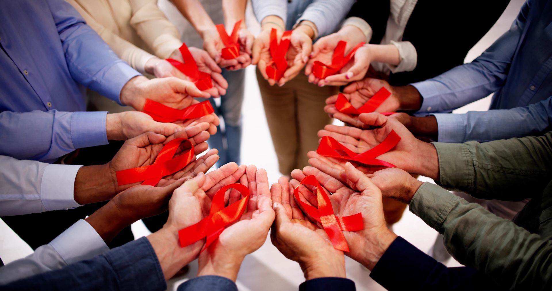 A group of people are holding red ribbons in their hands.