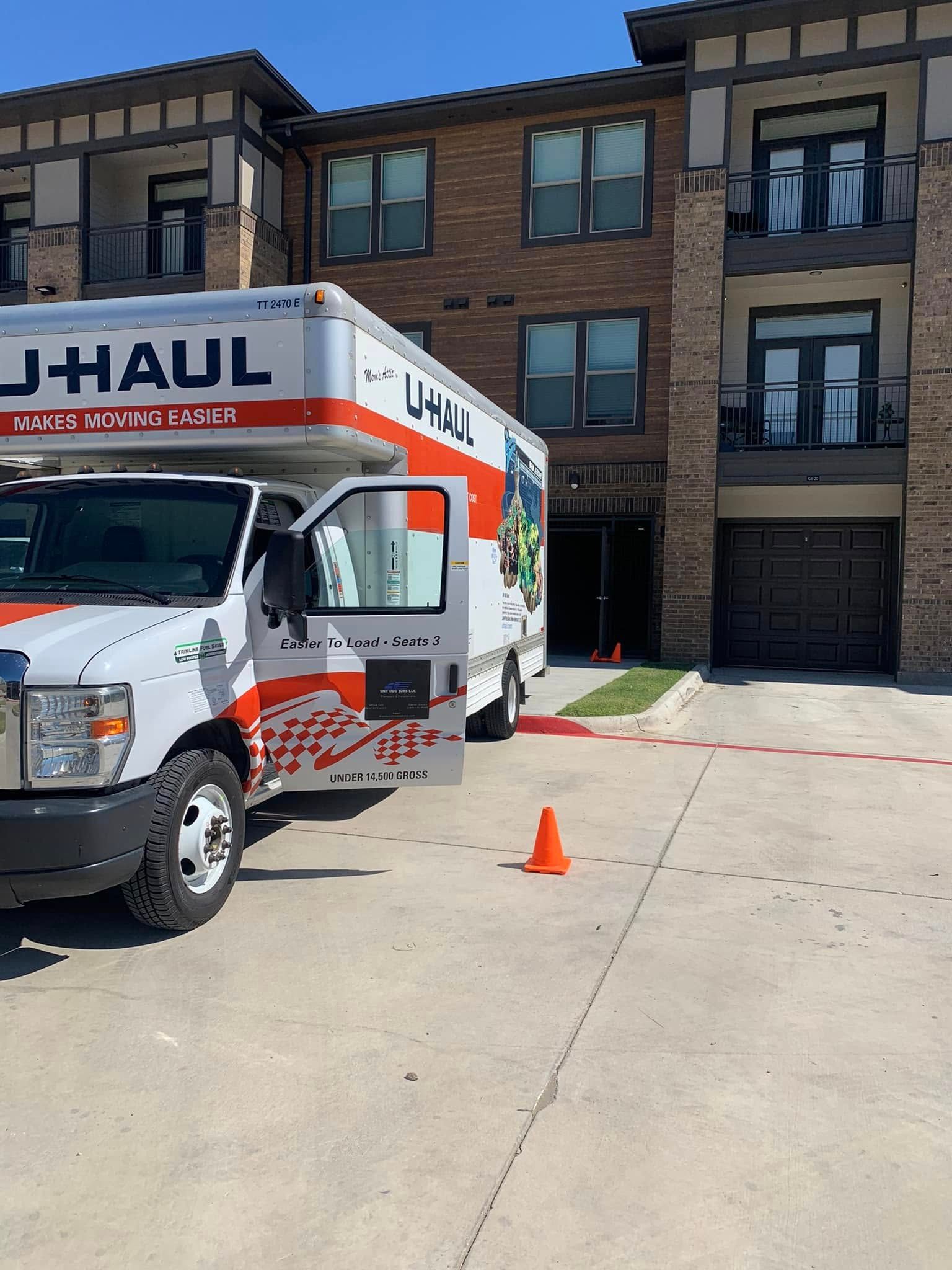 U-Haul truck parked outside an apartment building with an orange cone on the driveway