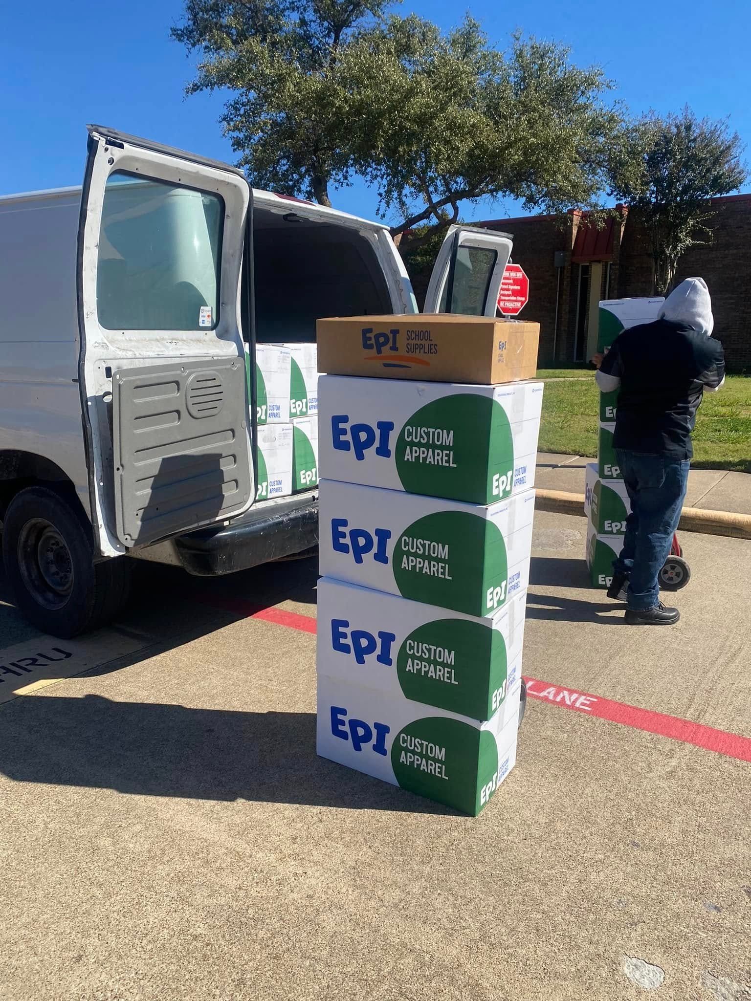 Open van with stacked EpiPen boxes and a person standing nearby outdoors