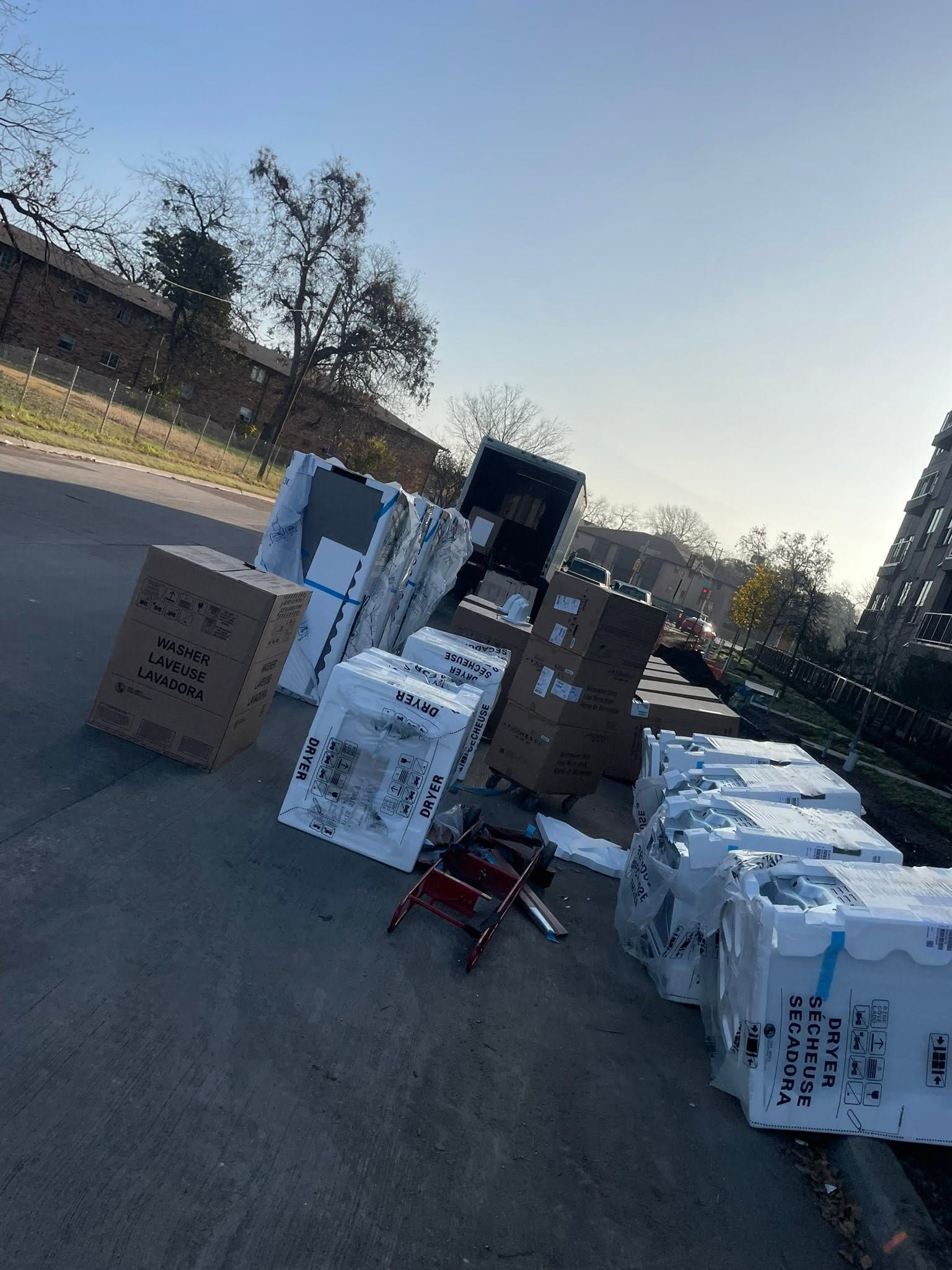 Boxes and bottled water stacked on a roadside near a parked truck at dusk