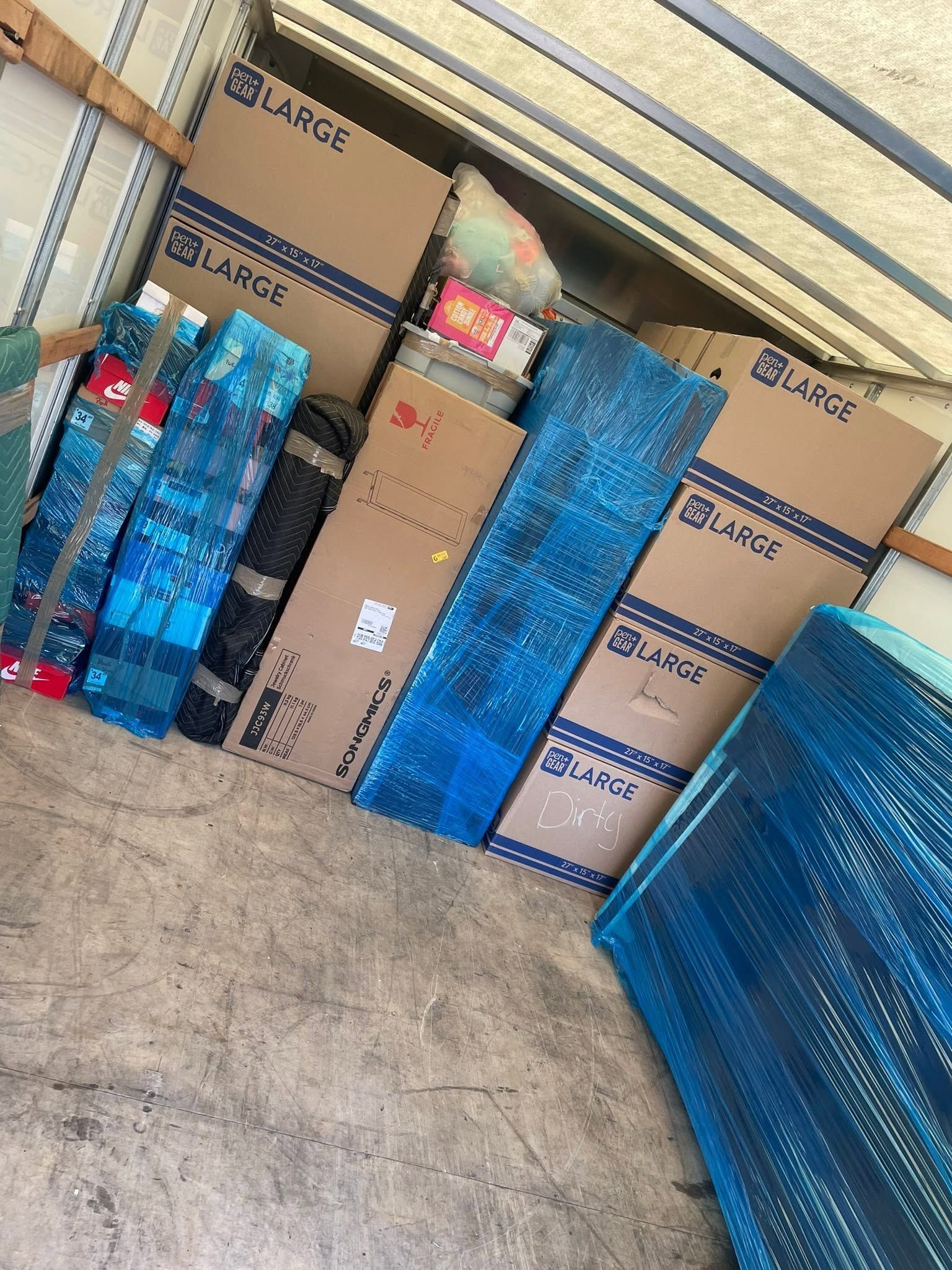 Stacked cardboard boxes and blue-wrapped packages in a warehouse or storage area.