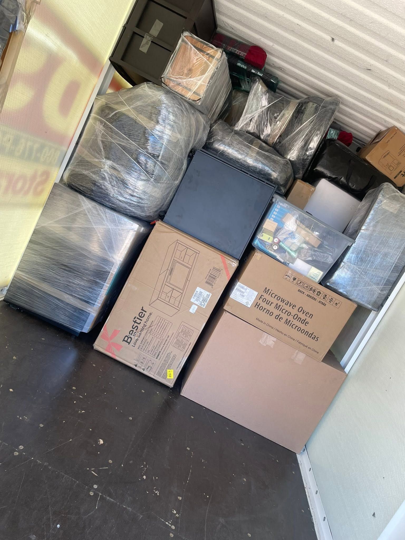 Moving truck packed with stacked wrapped furniture and cardboard boxes inside a cargo area