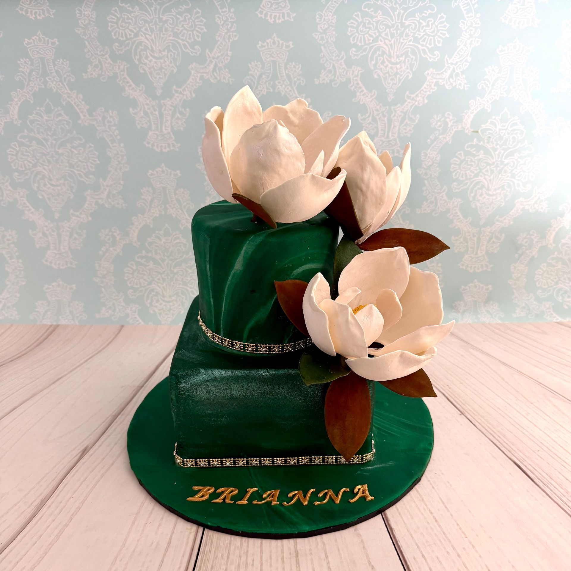 two tier birthday cake with marbled forest green fondant and hand made sugar southern magnolias.