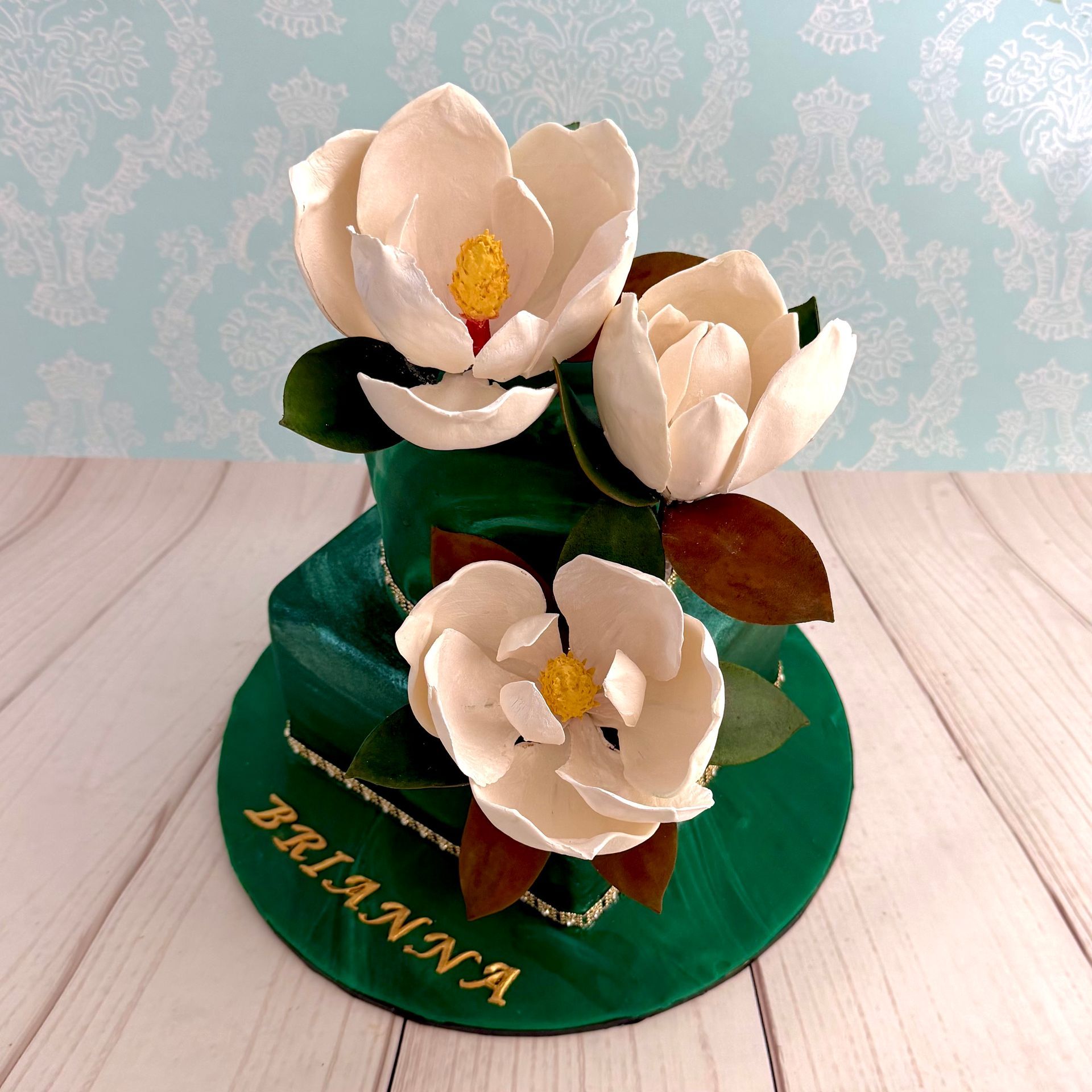 two tier birthday cake with marbled forest green fondant and hand made sugar southern magnolias.