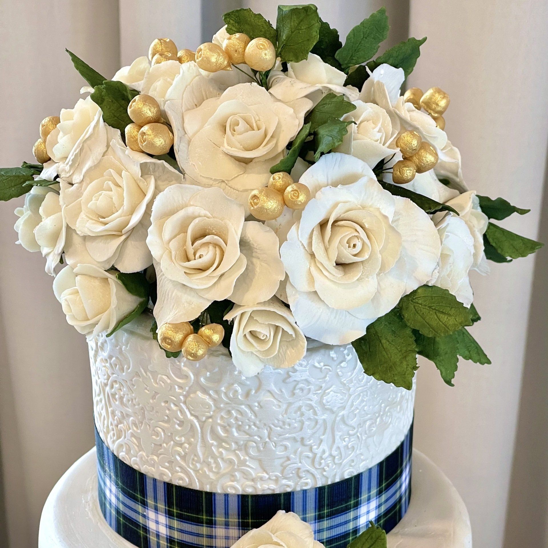 Close up of the top sugar flowers from the pearl white and tartan wedding cake.