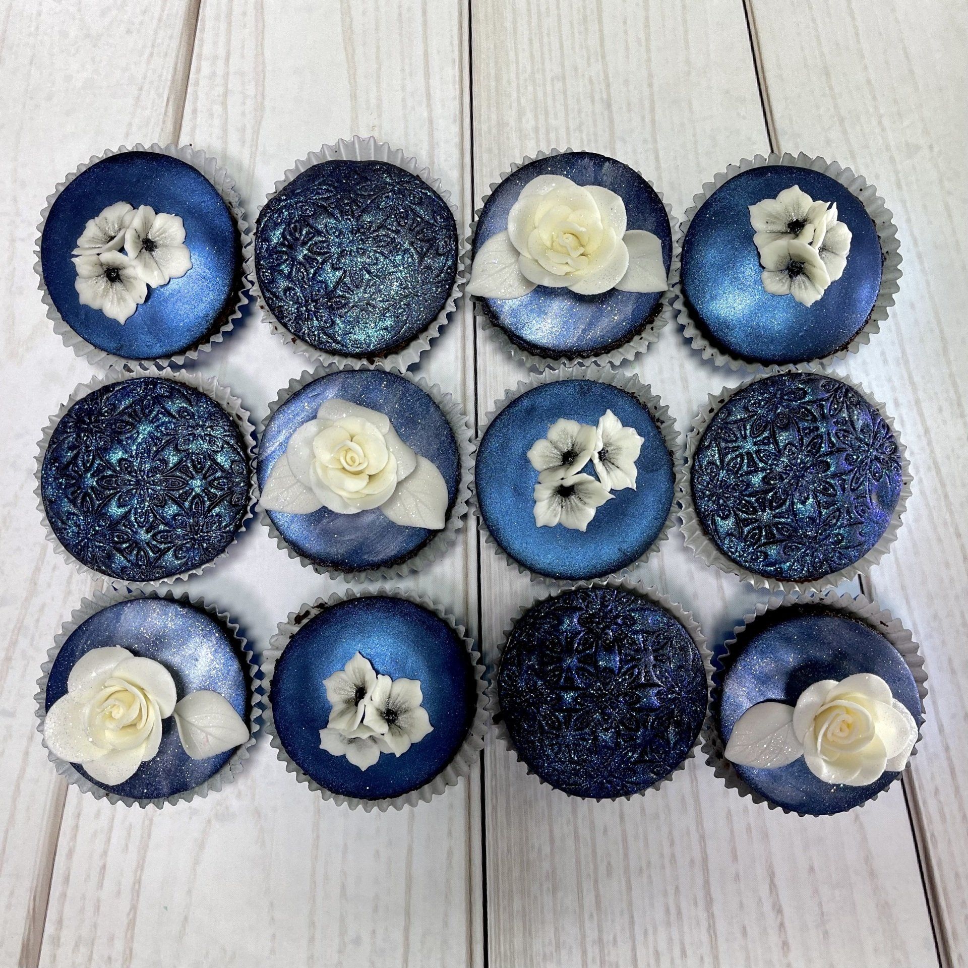 Elegant metallic navy cupcakes with white sugar flowers.