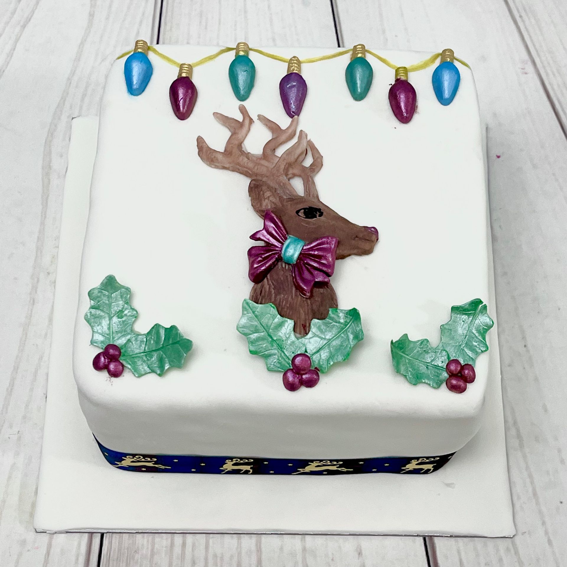 Chrristmas Cake Decorated with a Fondant Reindeer Holly and Christmas Lights 