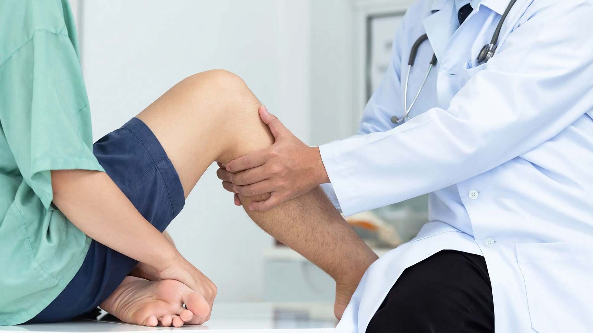 Doctor examining a patient’s bent knee in a clinic setting