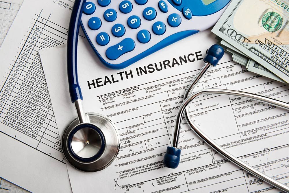 Health insurance documents with stethoscope, calculator, and U.S. dollar bills