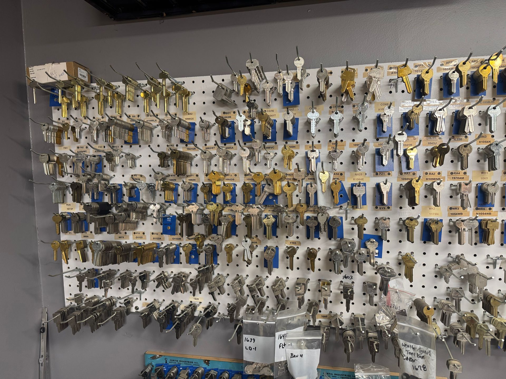 A pegboard displaying various keys for sale in a locksmith shop.