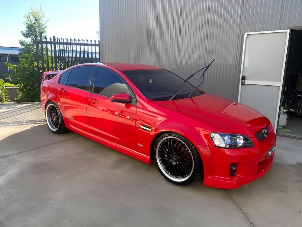 A Red Car Is Parked In Front Of A Garage Door — All Clean Auto Detailing In Caves Beach, NSW