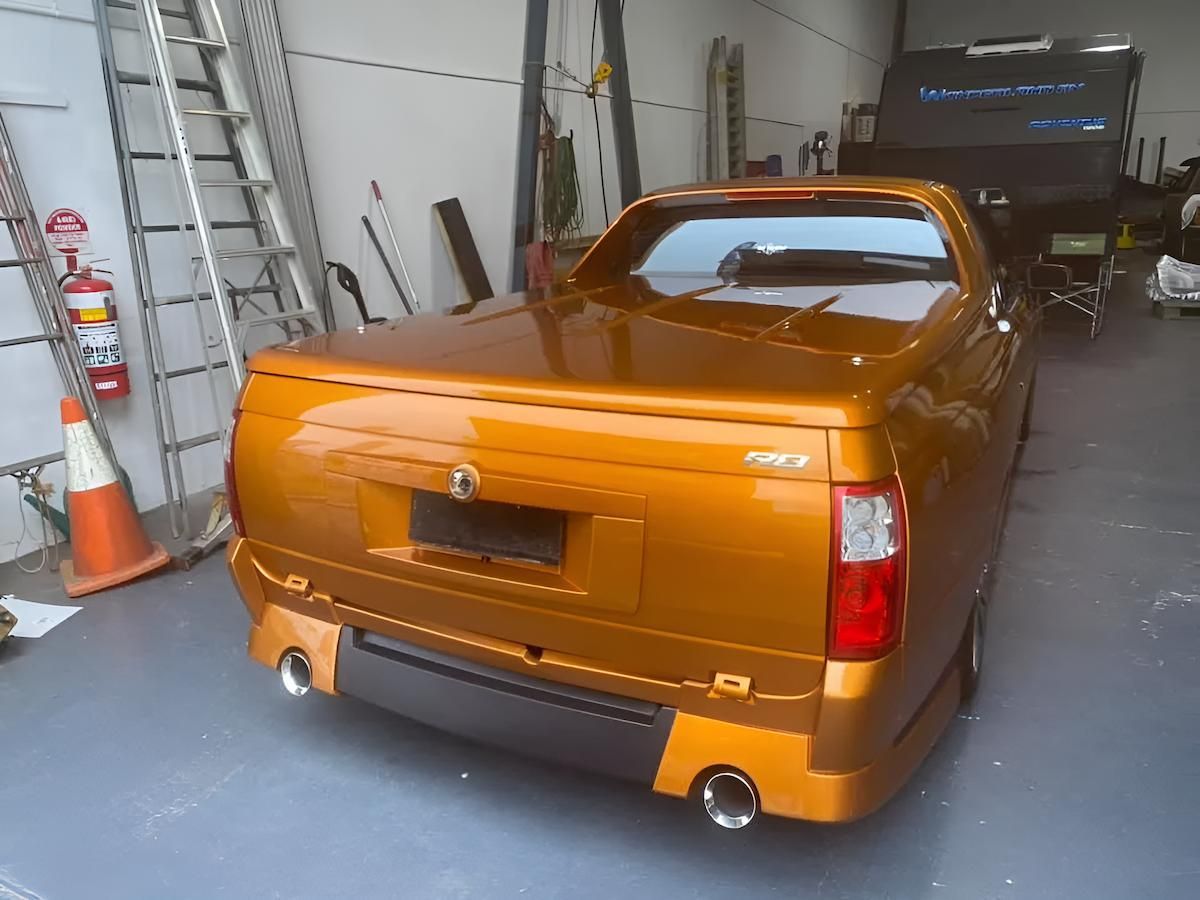 An Orange Truck Is Parked In A Garage Next To A Fire Extinguisher — All Clean Auto Detailing In Summerland Point, NSW