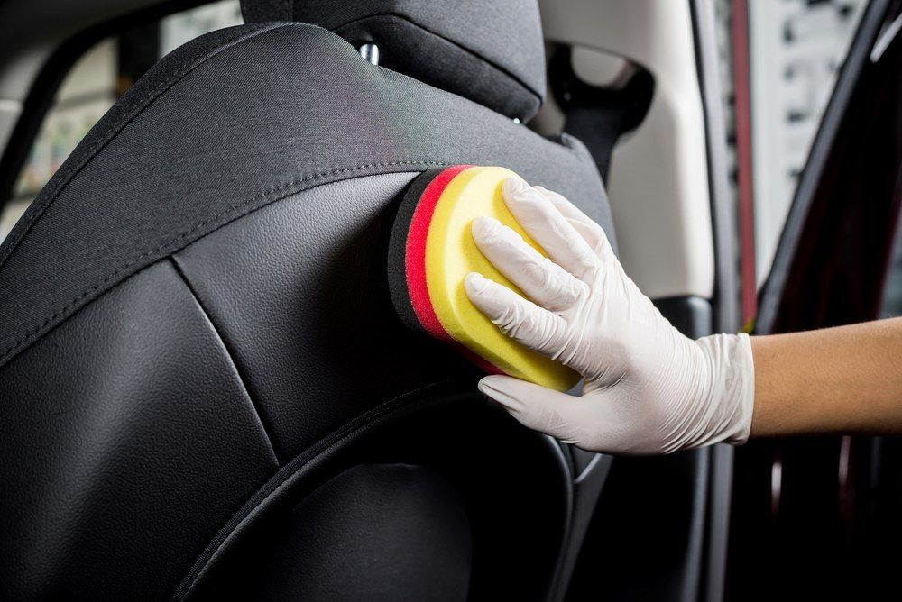 A Person Is Cleaning A Car Seat With A Sponge — All Clean Auto Detailing In Caves Beach, NSW