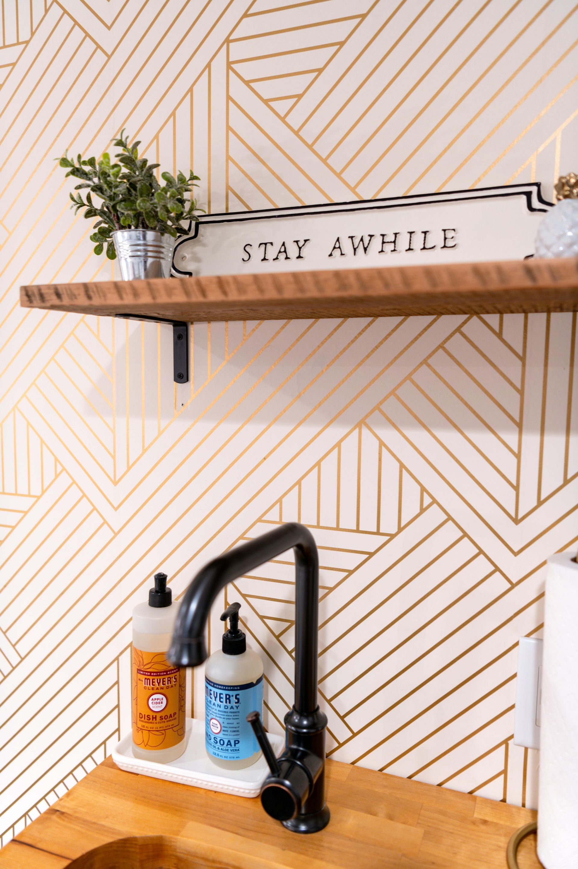 A bathroom with a sink and a sign that says stay awhile