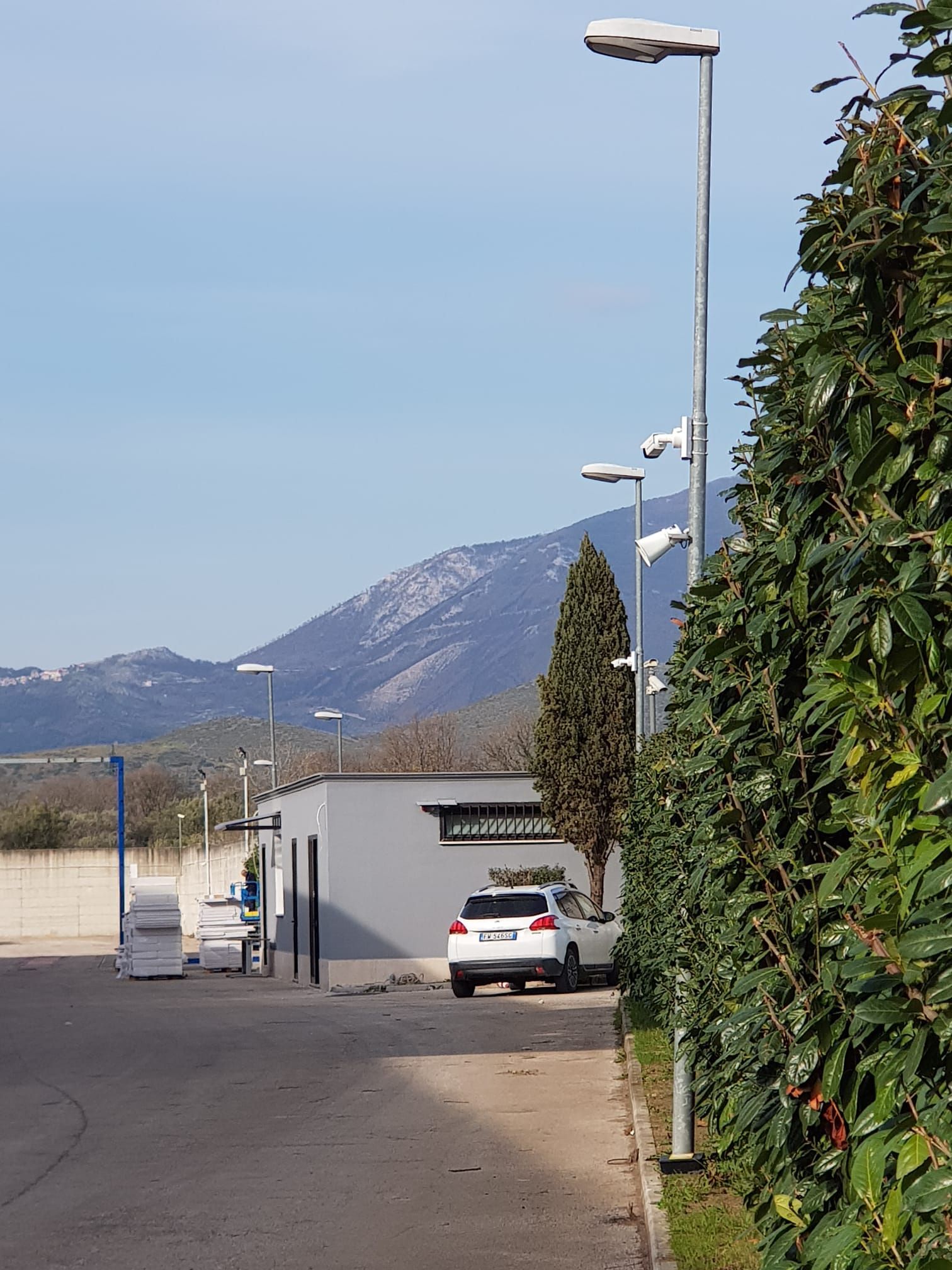 Un'auto bianca è parcheggiata davanti a un edificio con le montagne sullo sfondo