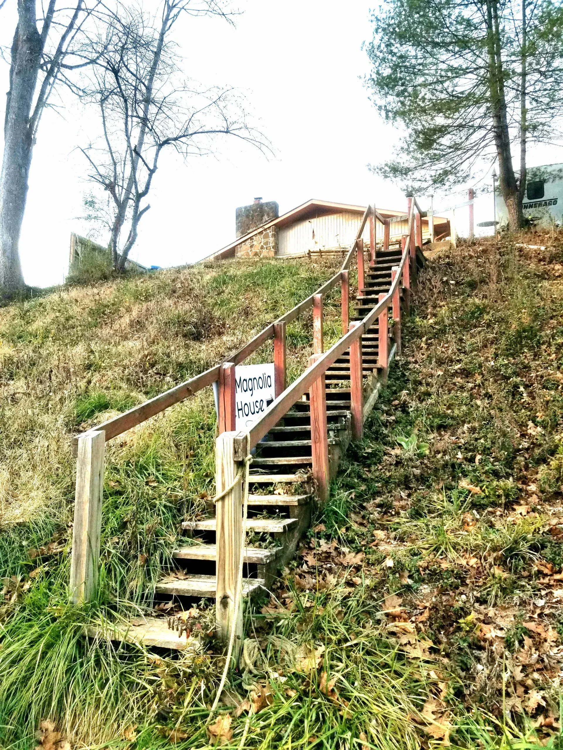 A set of wooden stairs leading up to a house on a hill.