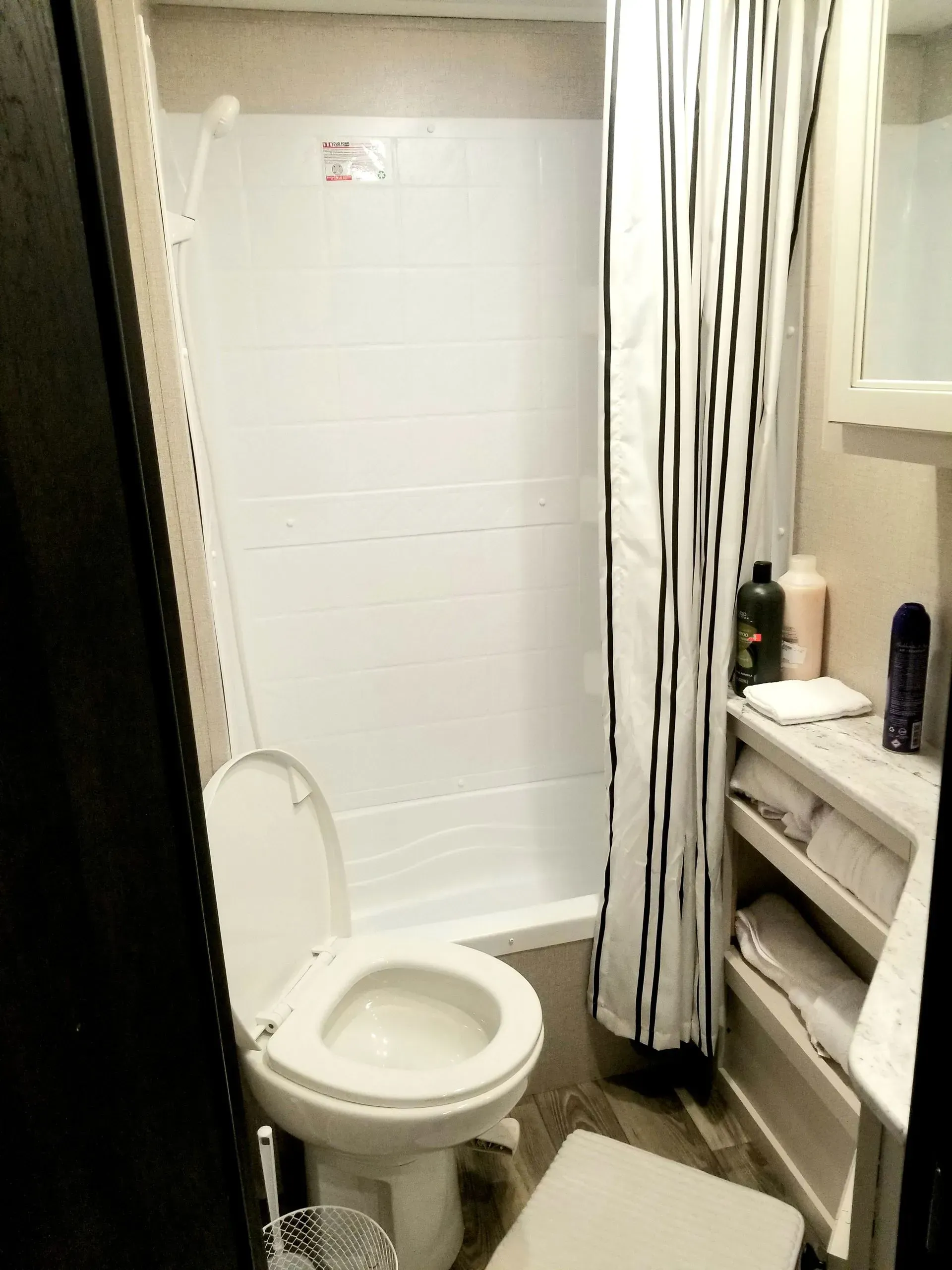 A bathroom with a toilet , shower and sink.