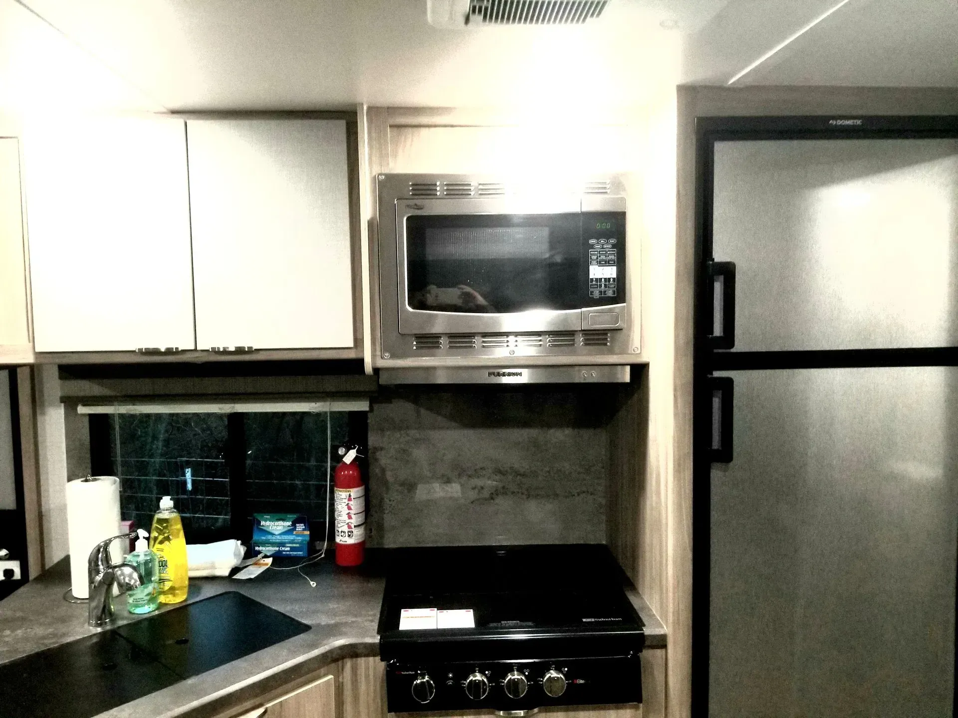 A kitchen with a stove a microwave and a refrigerator