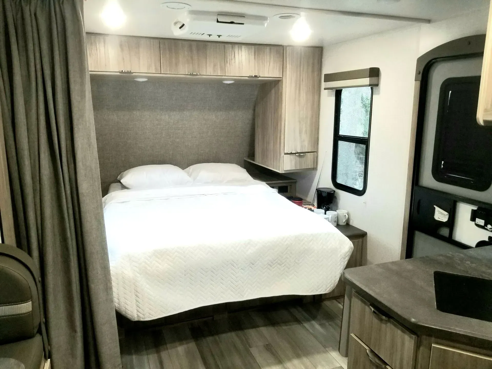 A bedroom in a rv with a bed and a window.