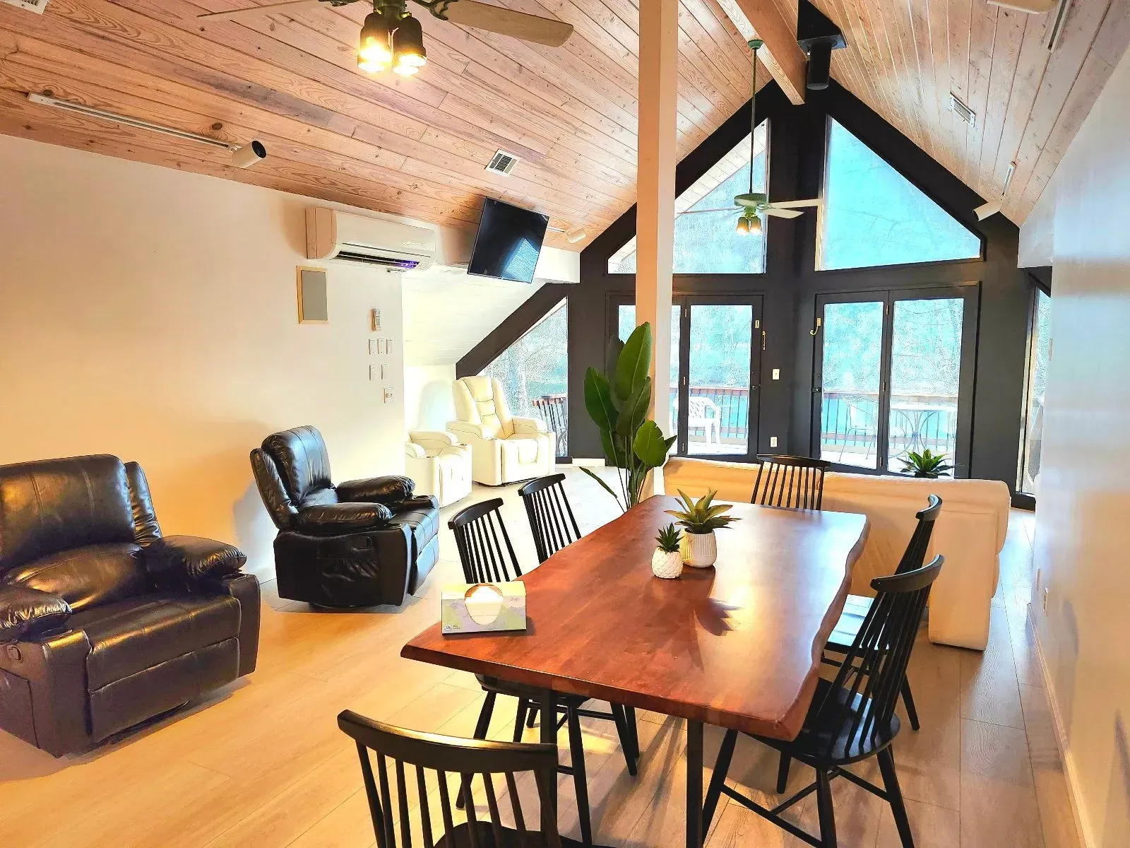 A living room with a dining table , chairs , and a ceiling fan.