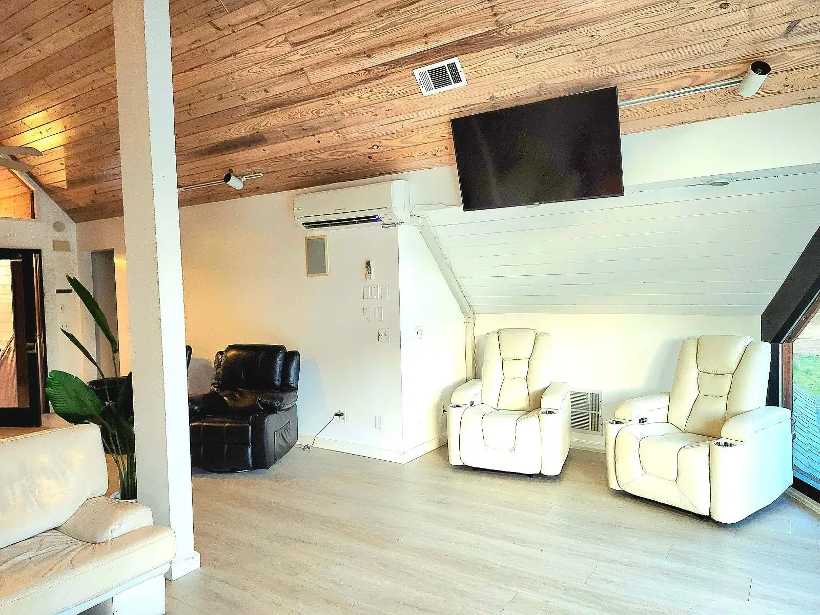 A living room with two recliner chairs and a flat screen tv on the ceiling.