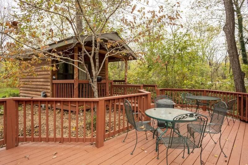 A wooden deck with a table and chairs in front of a cabin.