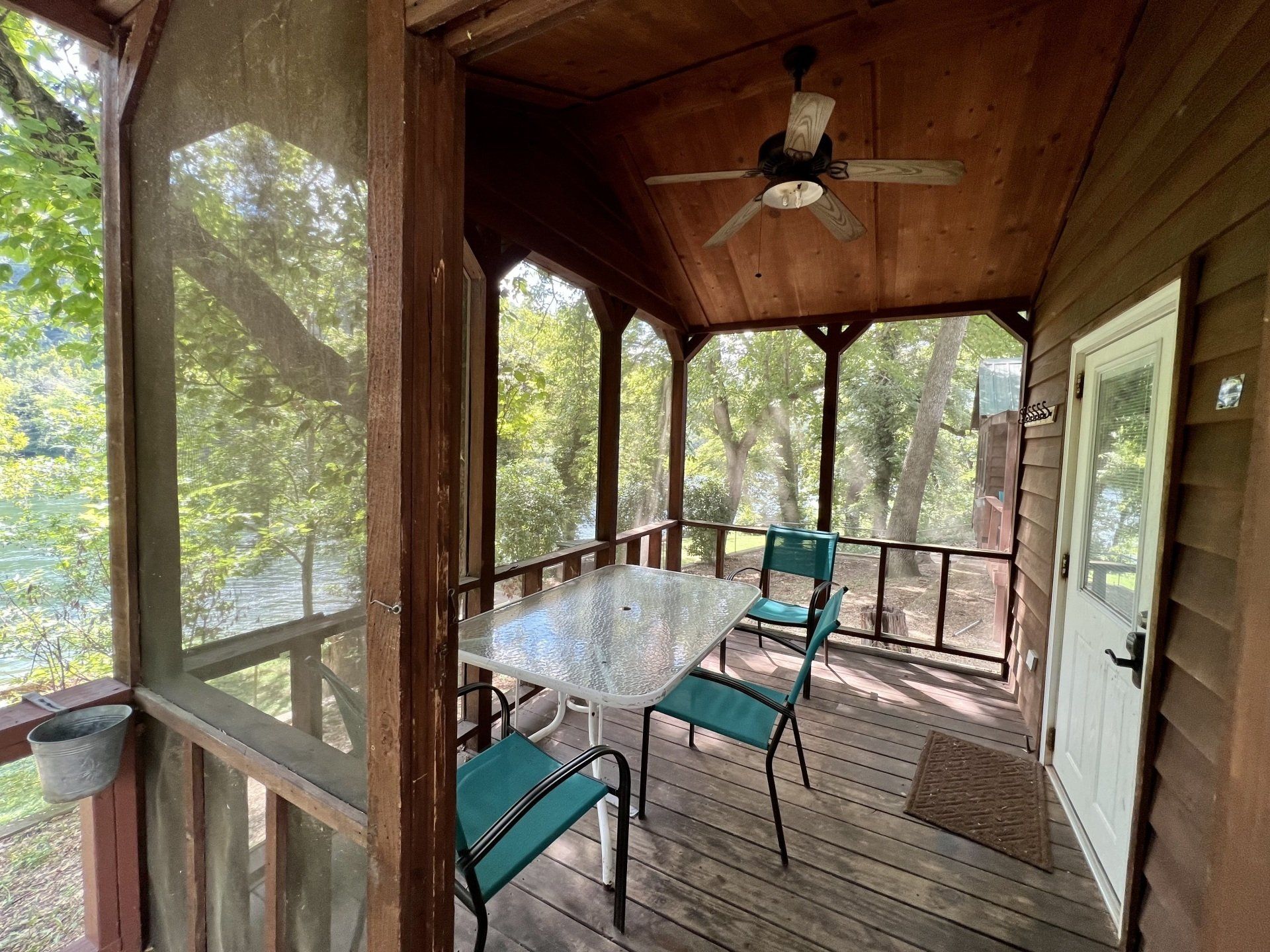 A screened in porch with a table and chairs and a ceiling fan copper johns resort