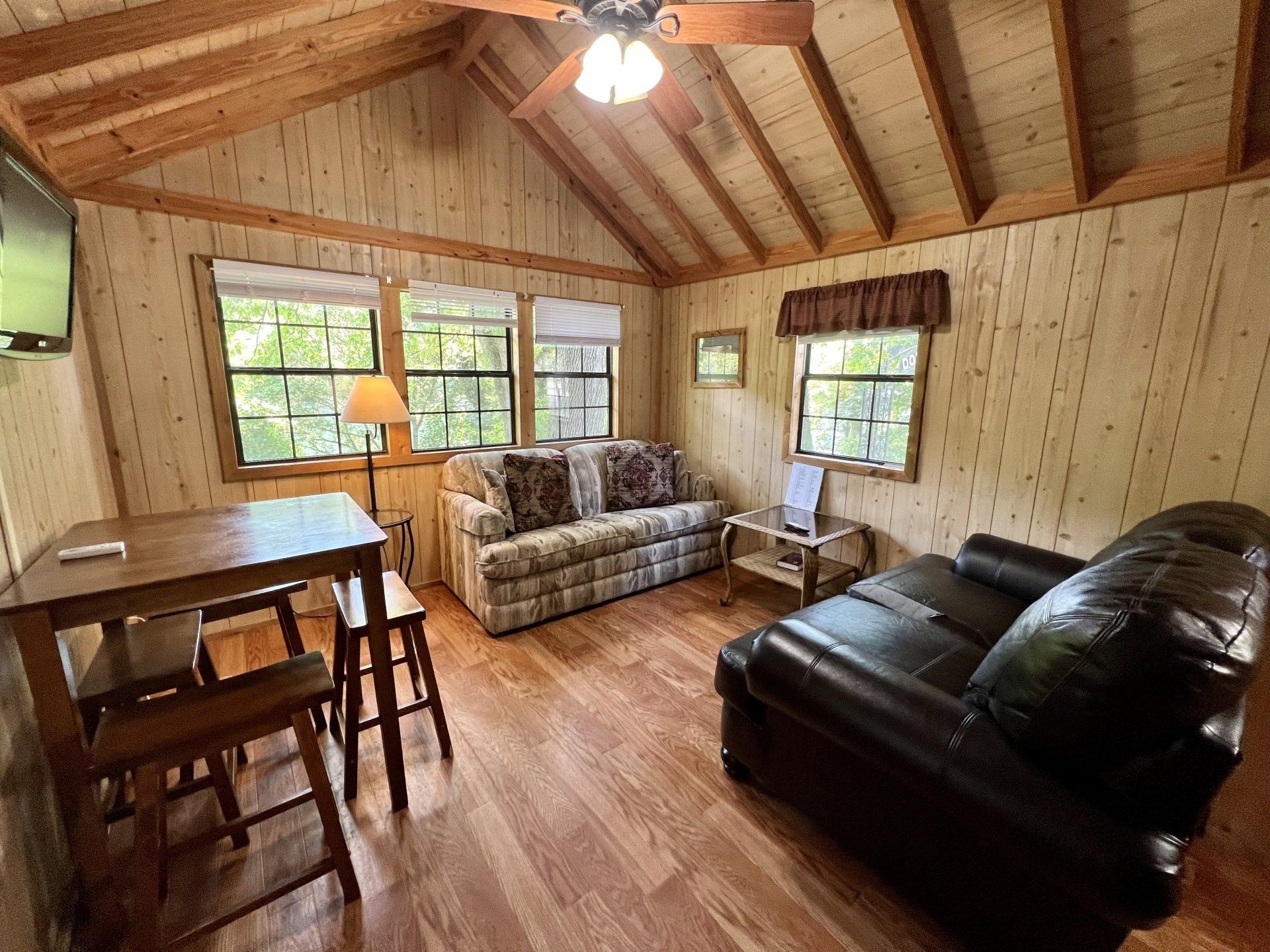 rustic humpy fly cabin living room with a couch , chair , table and television.