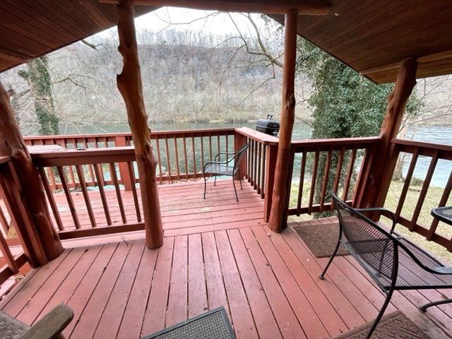 A wooden deck with chairs and a table overlooking a lake.