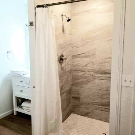 A bathroom with a walk in shower and a white shower curtain.