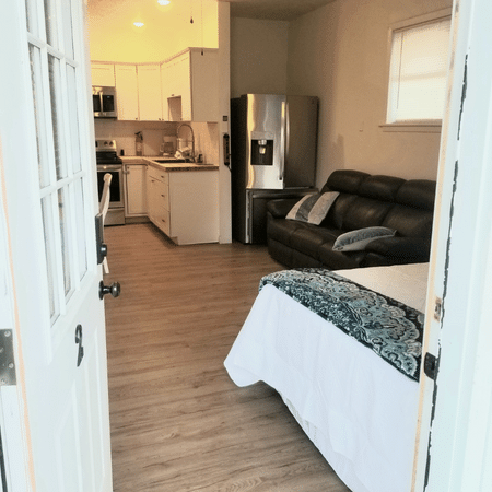 A bedroom with a bed a couch and a refrigerator